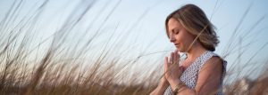 Emily Aarons praying in a field.